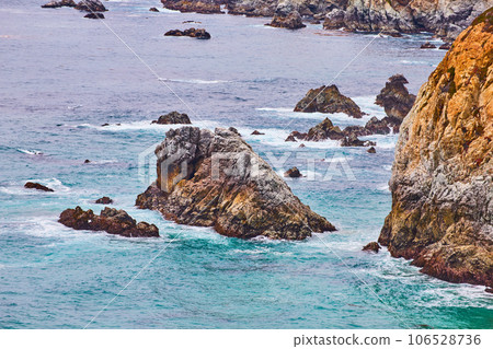 Beautiful rough cliff crags aerial of Pacific Ocean crashing against California harsh coast 106528736