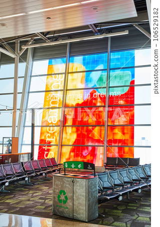 Metal recycling receptacle with empty airport terminal chairs and vibrant window art Metal recycling receptacle with empty airport terminal chairs and vibrant window art 106529182