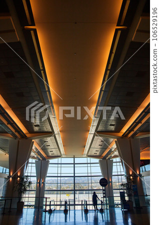 Person standing in large open hallway inside airport with unseen stairs leading to A gates 106529196