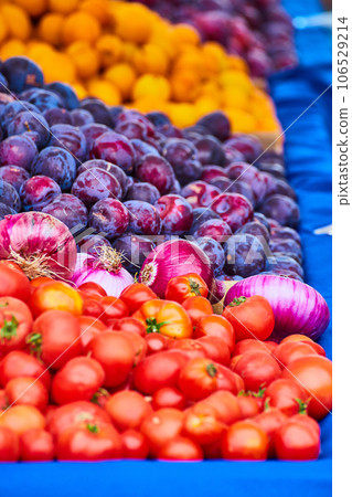 Colorful variety of fruits and vegies on blue tablecloth with tomatoes and onions and plums Colorful variety of fruits and vegies on blue tablecloth with tomatoes and onions and plums 106529214
