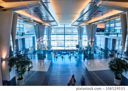 Open airport interior with blue and cream lighting and bright light from windows 106529533