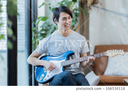Young man practicing guitar at home Young man practicing guitar at home 106530118