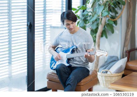 Young man practicing guitar at home Young man practicing guitar at home 106530119