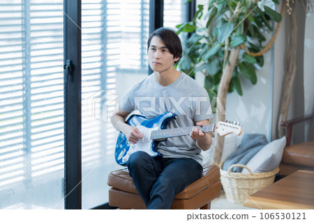 Young man practicing guitar at home 106530121