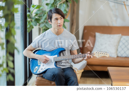 Young man practicing guitar at home Young man practicing guitar at home 106530137