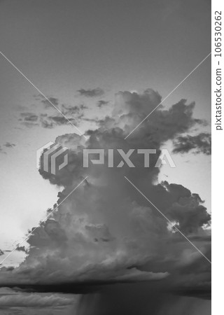 Cumulonimbus clouds rising in the late summer evening sky and rain pillars below, high-tone monochrome Cumulonimbus clouds rising in the late summer evening sky and rain pillars below, high-tone monochrome 106530262