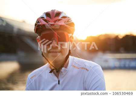 Man is wearing protective helmet, sunglasses and sportswear during evening ride in city. 106530469