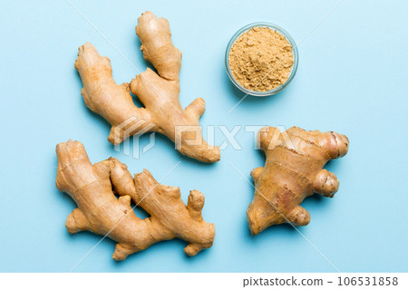 Finely dry Ginger powder in bowl with green leaves isolated on colored background. top view flat lay Finely dry Ginger powder in bowl with green leaves isolated on colored background. top view flat lay 106531858