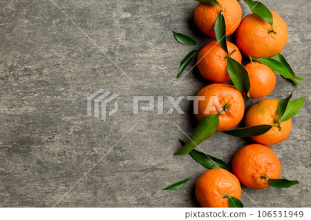 Many fresh ripe mandarin with green leaves on colored background, top view, space for text Many fresh ripe mandarin with green leaves on colored background, top view, space for text 106531949