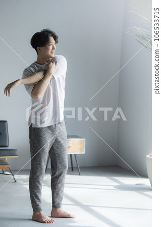 Vertical sunrise of a man stretching and stretching by the window Vertical sunrise of a man stretching and stretching by the window 106533715