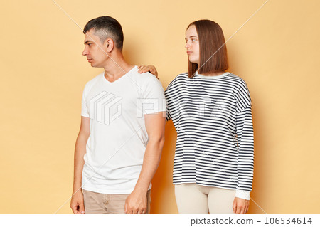 Funny woman trying to reconcile with offended man wearing casual clothing standing isolated over beige background family after arguing and quarrel. Funny woman trying to reconcile with offended man wearing casual clothing standing isolated over beige background family after arguing and quarrel. 106534614