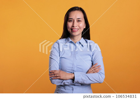 Portrait of smiling woman standing in arm crossed posing in studio over yellow background, smiling at camera during shoot. Cheerful filipino model with joyful expression having fun, enjoying free time Portrait of smiling woman standing in arm crossed posing in studio over yellow background, smiling at camera during shoot. Cheerful filipino model with joyful expression having fun, enjoying free time 106534831