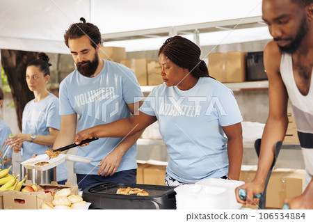 Multiethnic volunteers providing humanitarian aid, donating essential items and cooking for the needy and less fortunate. Hunger relief team helping the homeless, sick, and impoverished individuals. Multiethnic volunteers providing humanitarian aid, donating essential items and cooking for the needy and less fortunate. Hunger relief team helping the homeless, sick, and impoverished individuals. 106534884