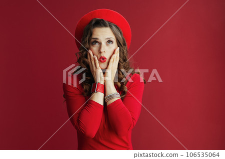 surprised elegant woman in dress and beret on red 106535064