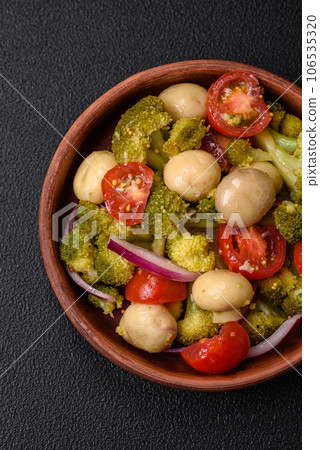 Delicious fresh salad with broccoli, cherry tomatoes, mushrooms, onions, salt, spices and herbs 106535320