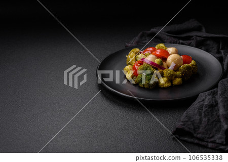 Delicious fresh salad with broccoli, cherry tomatoes, mushrooms, onions, salt, spices and herbs 106535338