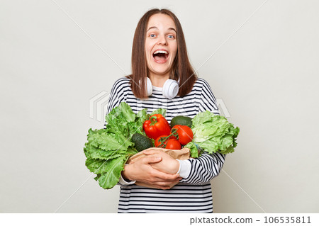 Happy positive woman embraces fresh vegetables and laughing expressing happiness optimistic emotions posing isolated over white background 106535811