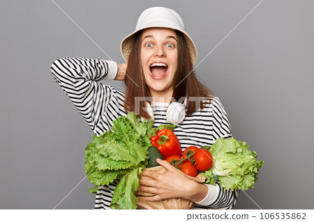Vegetable power, healthy life. Green diet, vibrant health. Overjoyed woman holding vegetable screaming with happiness isolated over gray background. Enjoy salad daily. 106535862