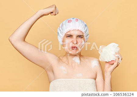 Delicate morning pampering. Displeased confused young woman in shower cap and wrapped in towel frowning face smelling armpit sweat isolated over beige background Delicate morning pampering. Displeased confused young woman in shower cap and wrapped in towel frowning face smelling armpit sweat isolated over beige background 106536124