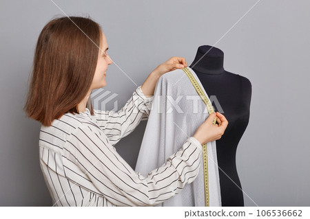 Entrepreneurial clothing venture. Custom garment creation. Cloth and textile production. Smiling woman needlewoman standing near new dress on mannequin iisolated over gray background. 106536662
