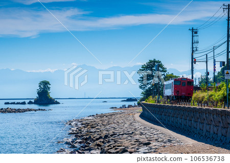 蔚藍的天空和平靜的海浪沿著海岸行駛的當地列車 | 從雨晴海岸到立山連峰的景色 | 富山縣高岡市 蔚藍的天空和平靜的海浪沿著海岸行駛的當地列車 | 從雨晴海岸到立山連峰的景色 | 富山縣高岡市 106536738