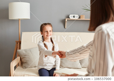 Specialist psychologist gentle handshake little kid creating safe and welcoming atmosphere for their session, working with child's problems in school and family. 106537000