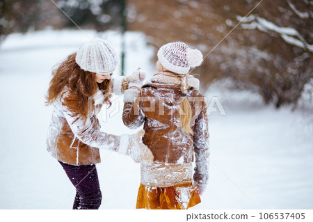 modern mother and daughter shaking snow off clothes modern mother and daughter shaking snow off clothes 106537405