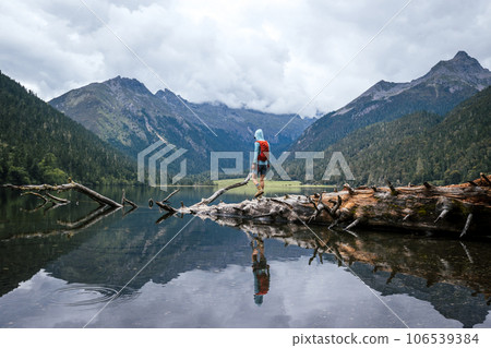 Woman walking on a one plank bridge in high altitude mountains Woman walking on a one plank bridge in high altitude mountains 106539384