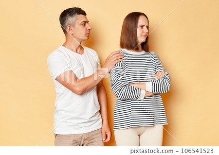 Can we try to make peace? Young boyfriend husband touching shoulders of offended girlfriend wife proposing to make peace, reconcile after quarrel isolated over beige background. Can we try to make peace? Young boyfriend husband touching shoulders of offended girlfriend wife proposing to make peace, reconcile after quarrel isolated over beige background. 106541523