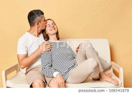 Affectionate young couple with eyes closed sitting on sofa at home romantic man kissing woman head with love, expressing dervotion and love. 106541879