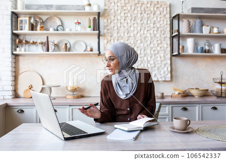 Young Muslim female teacher in hijab working from home, doing distance and online learning via video call from laptop. 106542337