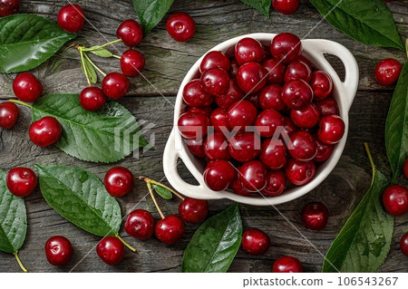 Fresh sweet cherries bowl with leaves on wooden desktop table. water drops on Fresh sour cherry sakura berries 106543267