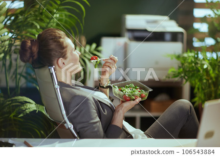 relaxed business woman in green office eating salad 106543884