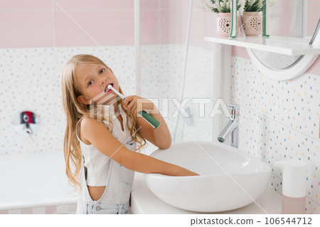 Cute girl brushes her teeth in the bathroom hygiene concept 106544712