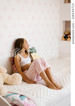 Cute girl sitting in pajamas sits in the morning on the bed Cute girl sitting in pajamas sits in the morning on the bed 106544714