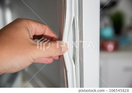 Torn and damaged sealing gum on the refrigerator door. Replacing the old sealing rubber with a new one Torn and damaged sealing gum on the refrigerator door. Replacing the old sealing rubber with a new one 106545828