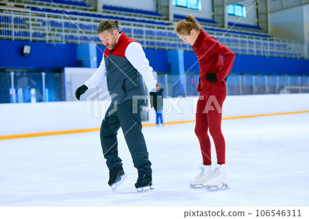 Professional skater, man training girl, learning figure skating activity on ice rink arena. Sport lessons with coach 106546311