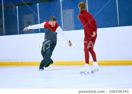 Professional skater, man training girl, learning figure skating activity on ice rink arena. Sport lessons with coach Professional skater, man training girl, learning figure skating activity on ice rink arena. Sport lessons with coach 106546345