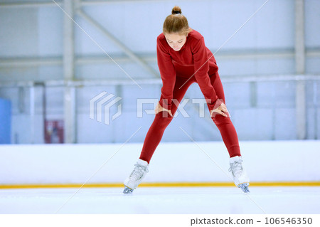 Girl in red sportswear, figure skating athlete standing on ice rink area and resting after hard training Girl in red sportswear, figure skating athlete standing on ice rink area and resting after hard training 106546350