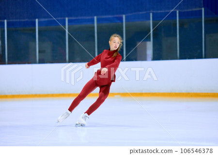 Concentrated and motivated teen girl in red sportswear training, skating on ice rink arena. Figure skating athlete Concentrated and motivated teen girl in red sportswear training, skating on ice rink arena. Figure skating athlete 106546378
