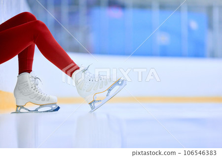 Close-up cropped image of female legs in red leggings and white skates on ice skate arena. Training and skating 106546383