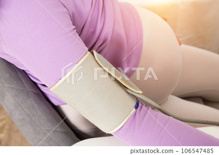 Measurement of pressure in a pregnant girl with an automatic tonometer. Lowering blood pressure during pregnancy. Hypotension, close-up Measurement of pressure in a pregnant girl with an automatic tonometer. Lowering blood pressure during pregnancy. Hypotension, close-up 106547485