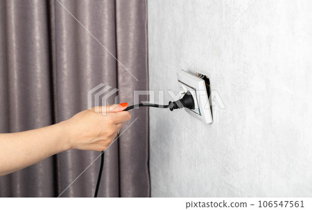 The girl incorrectly removes the electric plug from the socket and breaks the socket. Danger of electric shock, close-up. Copy space for text The girl incorrectly removes the electric plug from the socket and breaks the socket. Danger of electric shock, close-up. Copy space for text 106547561