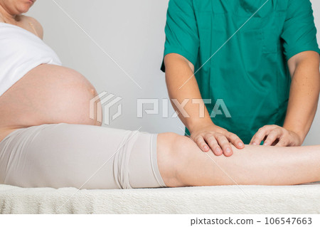 Doctor masseur makes a foot massage to a pregnant girl from pain in the joints of the legs and varicose veins. Relieve fatigue and pain. 106547663