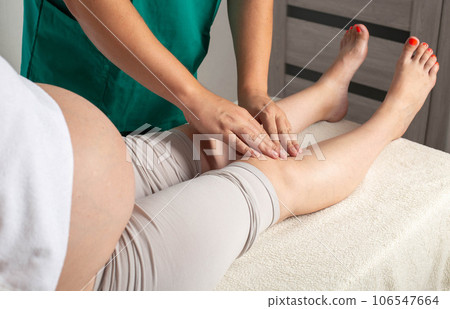 Doctor masseur makes a foot massage to a pregnant girl from pain in the joints of the legs and varicose veins. Relieve fatigue and pain. 106547664