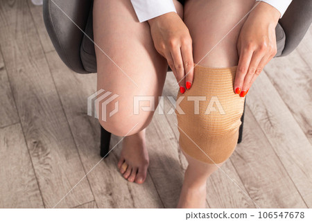 Orthopedic medical kneecap on the leg of a girl. Fixation and support of the knee joint after injury. Orthopedic medical kneecap on the leg of a girl. Fixation and support of the knee joint after injury. 106547678