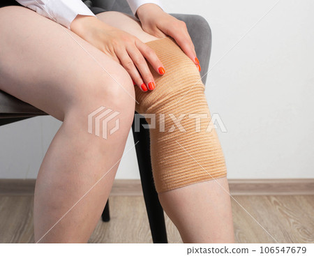 Orthopedic medical kneecap on the leg of a girl. Fixation and support of the knee joint after injury. Orthopedic medical kneecap on the leg of a girl. Fixation and support of the knee joint after injury. 106547679