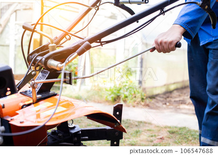The worker adjusts the gear changes in the walk-behind tractor before running. Copy space for text, transmission The worker adjusts the gear changes in the walk-behind tractor before running. Copy space for text, transmission 106547688