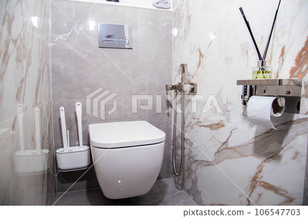 Modern washroom interior with wall hung toilet and gray porcelain stoneware tiles. Aroma diffuser for toilet Modern washroom interior with wall hung toilet and gray porcelain stoneware tiles. Aroma diffuser for toilet 106547703