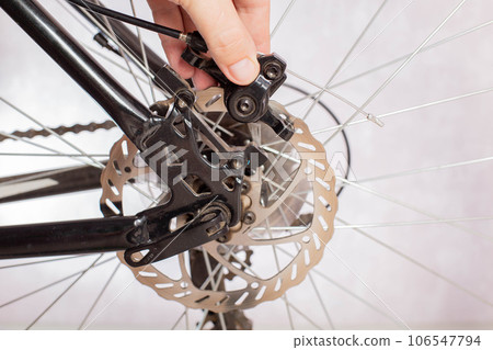 Removing the brake caliper on a bike with disc brakes. Replacement and adjustment of brake pads. Bicycle service. Copy space for text Removing the brake caliper on a bike with disc brakes. Replacement and adjustment of brake pads. Bicycle service. Copy space for text 106547794